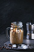 Glass mason jar of ice coffee with ice cream and chocolate sauce