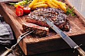 Sliced Steak Ribeye with french fries on serving board block on wooden background