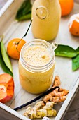 Winter-Smoothie mit Mandarine, Sharon, Kurkuma und Ingwer auf Holztablett