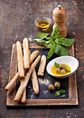 Antipasti: Brotsticks mit Oliven und Olivenöl auf Vintage-Schieferkreidetafel