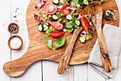 Zutaten für Salat mit Blattsalat, Tomaten und Gurken auf Holzbrett