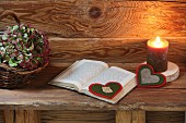 Hand-crafted, heart-shaped felt bookmark next to lit candle on rustic wooden bench