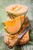 Cataloupe-Melone, halbiert und in Spalten geschnitten auf Holzbrett