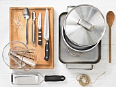 Various kitchen utensils: pot, baking dish, grater, kitchen string, measuring cup, knife, toothpick