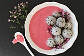 A pink smoothie bowl with dragon fruit balls