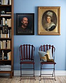Two antique-style portraits in different frames on light blue wall