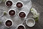 Chocolate cups filled with date caramel with sea salt on a white paper and grey background
