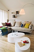 Two organically formed coffee tables in front of oatmeal sofa with colourful scatter cushions