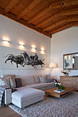 Large picture of bulls above sofa in living room with wood-beamed ceiling