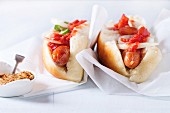 Homemade hot dogs on baking papper with tomato sauce, onion, pepper and mustard on light blue wooden background