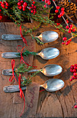 Silver spoons decorated with juniper sprigs and red ribbons for Christmas