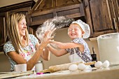 A mother and daughter having a food fight with flour in the kitchen