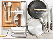 Various kitchen utensils: meat grinder, pasta machine, pots, pan