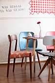 Various retro chairs around Gerbera, meringue and sugar bowl on table