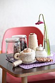 Needle-felted a cup of cappuccino, chocolate, sugar bowl, Gerbera daisy, yarn and glass jars on table