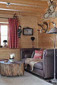Sofa and tree-stump table on castors in corner of room in wooden cabin
