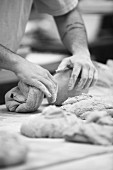 A baker kneading dough in his bakery