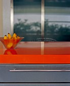 Bananen in Glasschüssel auf orangefarbener Küchenarbeitsplatte