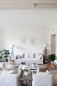 White loose-covered furniture and coffee table in shabby-chic living area