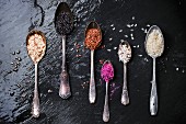 Set of unusual rice in vintage spoons over dark surface
