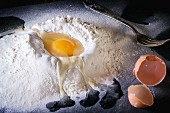 Teigzutaten: Mehlhäufchen mit aufgeschlagenem Ei