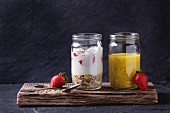 Muesli, strawberries and yogurt with mango smoothie in glass mason jars with fresh strawberry