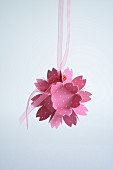 Pink paper flower hung from ribbon