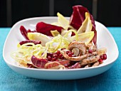 A chicory salad with strips of turkey and pomegranate seeds