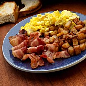 Scrambled egg with American bacon and fried potatoes