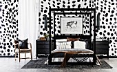 Double bed with black frame and black nightstand against wall with Dalmatian wallpaper