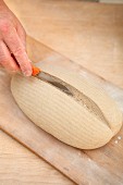 Bread dough being scored with a knife