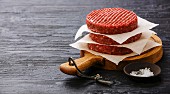 Raw Ground beef meat Burger cutlets and on black burned wooden background copy space