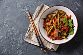 Stir fry beef with vegetables in bowl on dark stone background