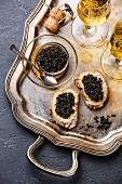 Sturgeon black caviar, sandwiches and champagne on silver tray