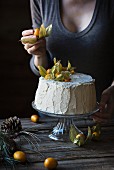 Frau dekoriert Chiffon-Cake mit Physalis