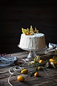 Chiffon-Cake mit Physalis auf Tortenständer und Holztisch