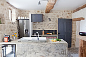 Exposed stone walls, beams and masonry counter in rustic kitchen