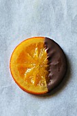 Candied orange slices coated with dark chocolate on white background, top view