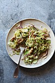 Shredded brussels sprouts salad with red onion and walnuts on a plate, top view
