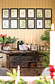 A Christmas buffet served on an old workbench with drawers, below a series of framed illustrations