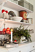 Lit candle on zinc box below bracket shelves