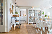 Windsor chairs at dining table in front of display case and open kitchen door