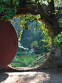 Blick in den üppigen Garten durch ein rundes Tor