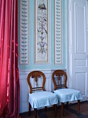 Two chairs against painted panelled wall