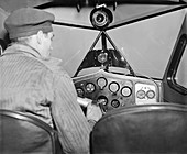 Pilot in cockpit with instrument landing system, 1937