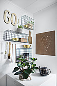 Wire baskets mounted on walls and used as shelves for kitchen utensils and ornaments
