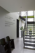 Vintage cinema seats and metal staircase in foyer with epoxy resin floor and grey walls