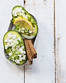 Healthy lunch: stuffed avocado with cottage cheese, rucola sprouts, rye bread and lemon