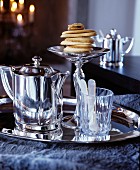 Silver tray with a silver jug, a small glass and a stack of pastries