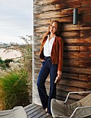 A red-haired woman wearing a brown suede blazer, a white blouse and high-waisted jeans